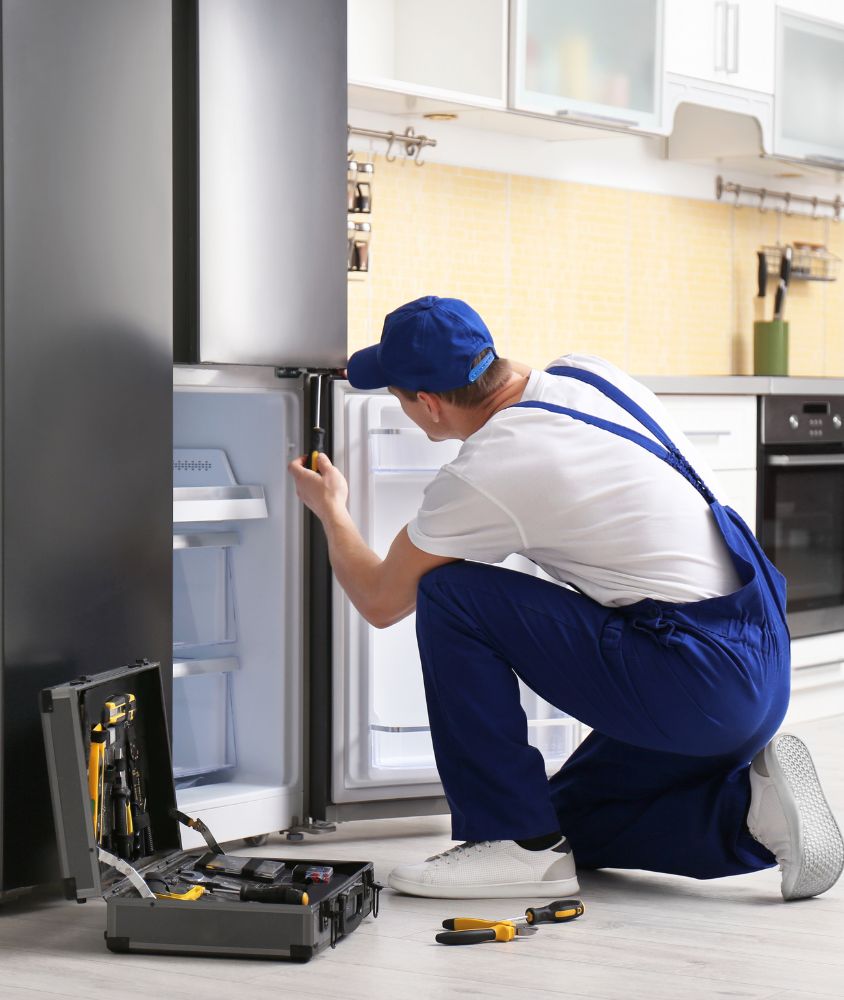 Tecnico fazendo manutencao em geladeira aberta na cozinha